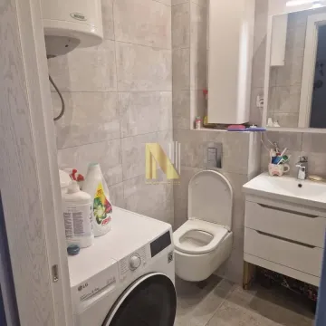 Manje kupatilo sa veš mašinom, toaletom i umivaonikom obloženo keramičkim pločicama. - image 15