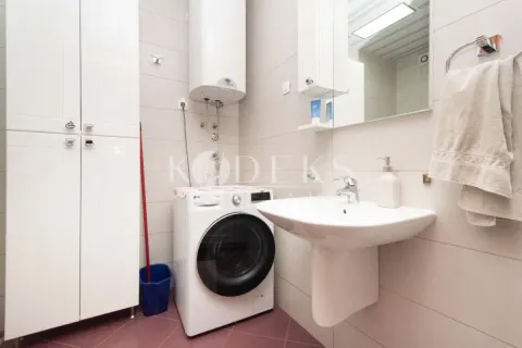 Bathroom with a sink, washing machine, water heater and white cabinet. - image 6