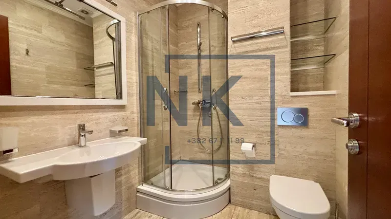 Bathroom equipped with a shower cabin, washbasin, toilet bowl, and mirror.