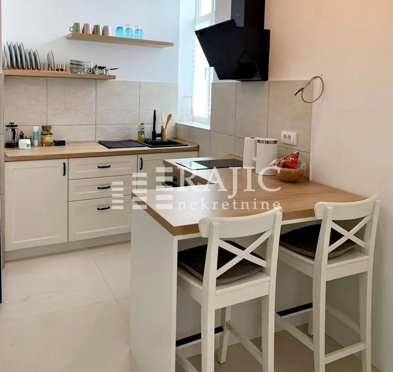 Modern kitchen with white cabinetry, a breakfast bar, and wooden details.