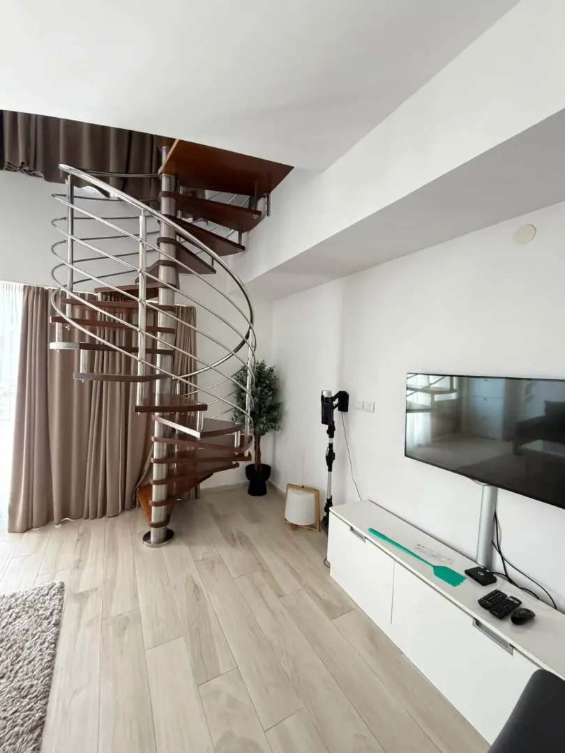 Living room with wooden spiral staircase and TV unit.