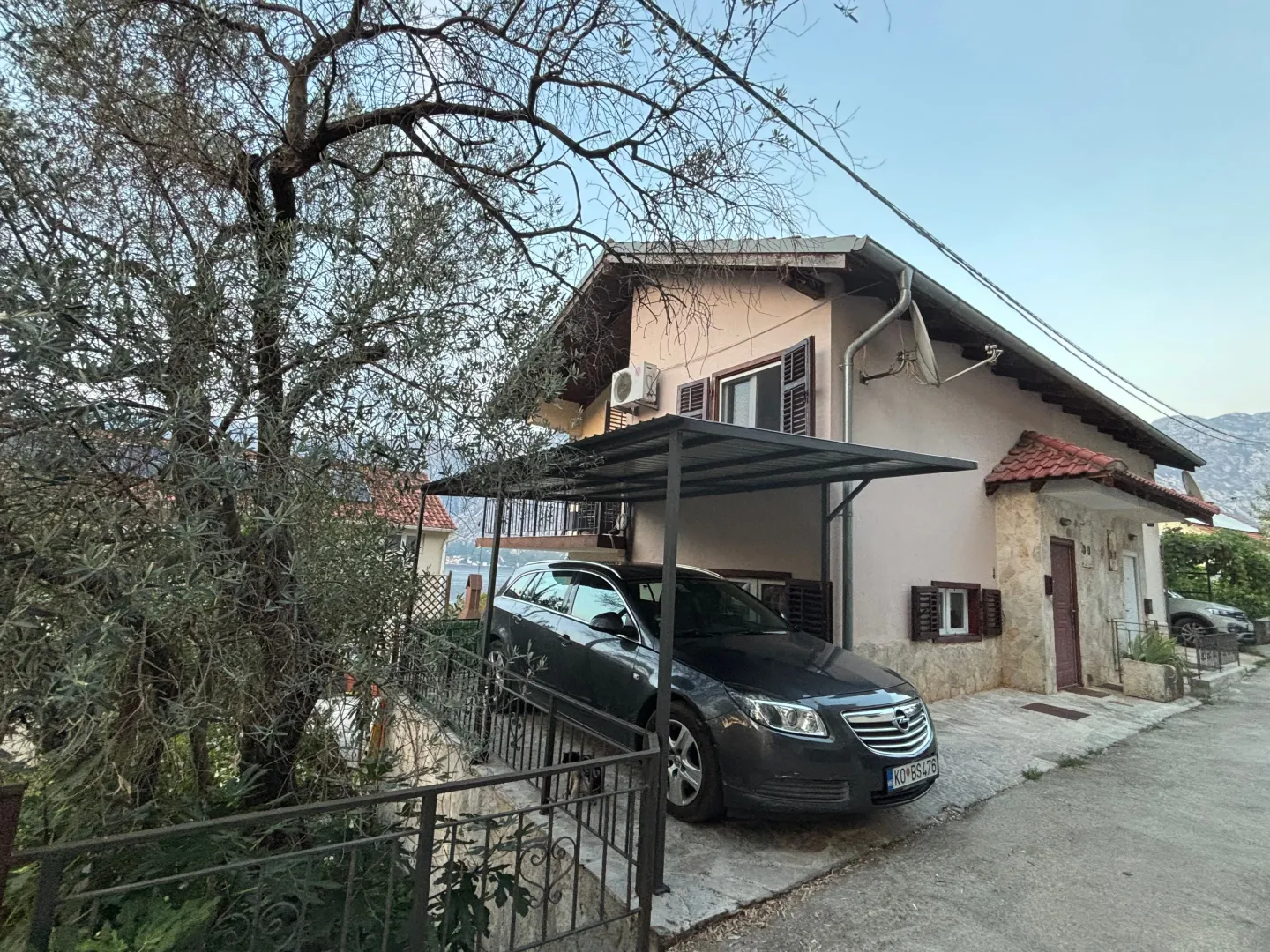 Spoljašnji izgled kuće sa dvorištem i parkingom.