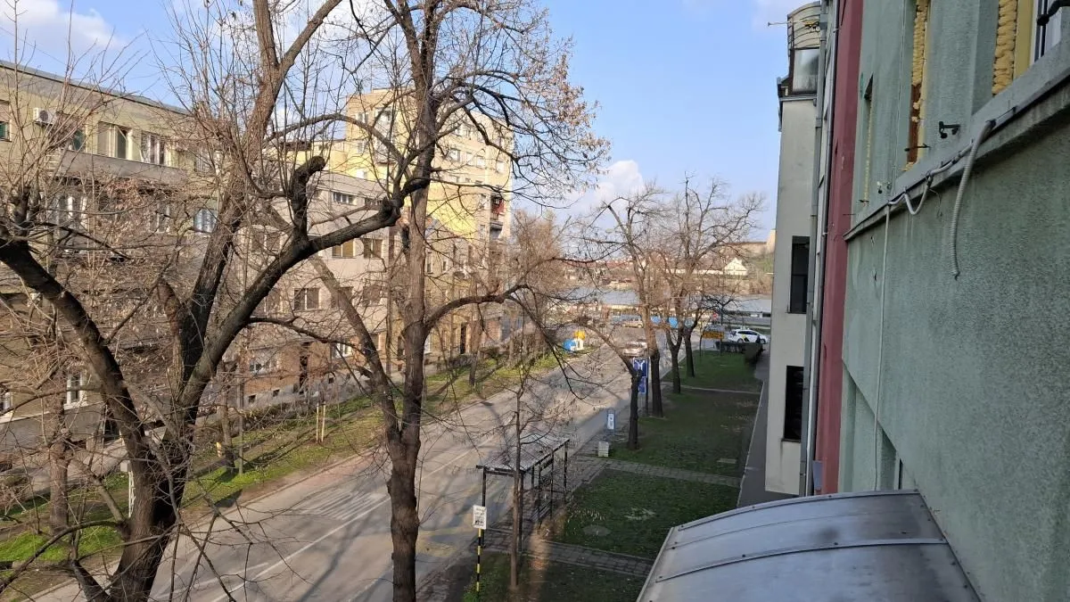 Pogled sa terase na ulicu, okolne zgrade i drveće.