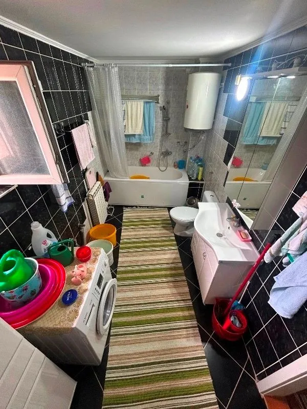Bathroom with a bathtub, sink, toilet, and washing machine.