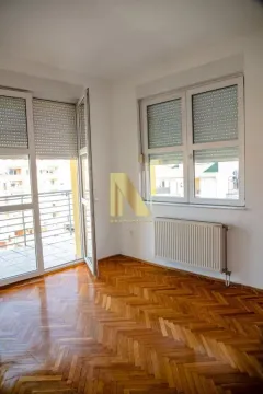 Prazna prostorija sa parketom na podu, radijatorom i izlazom na terasu. - image 9