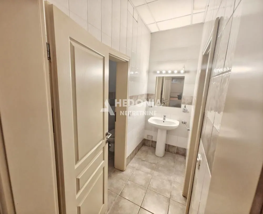 View of the bathroom with a sink, mirror and open door.