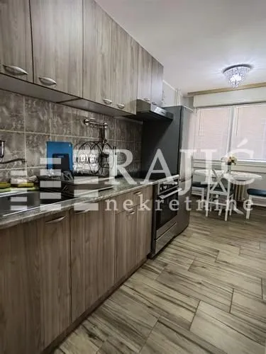 Small kitchen with wooden cabinets and a dining area in the background.