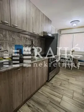 Small kitchen with wooden cabinets and a dining area in the background. - image 9