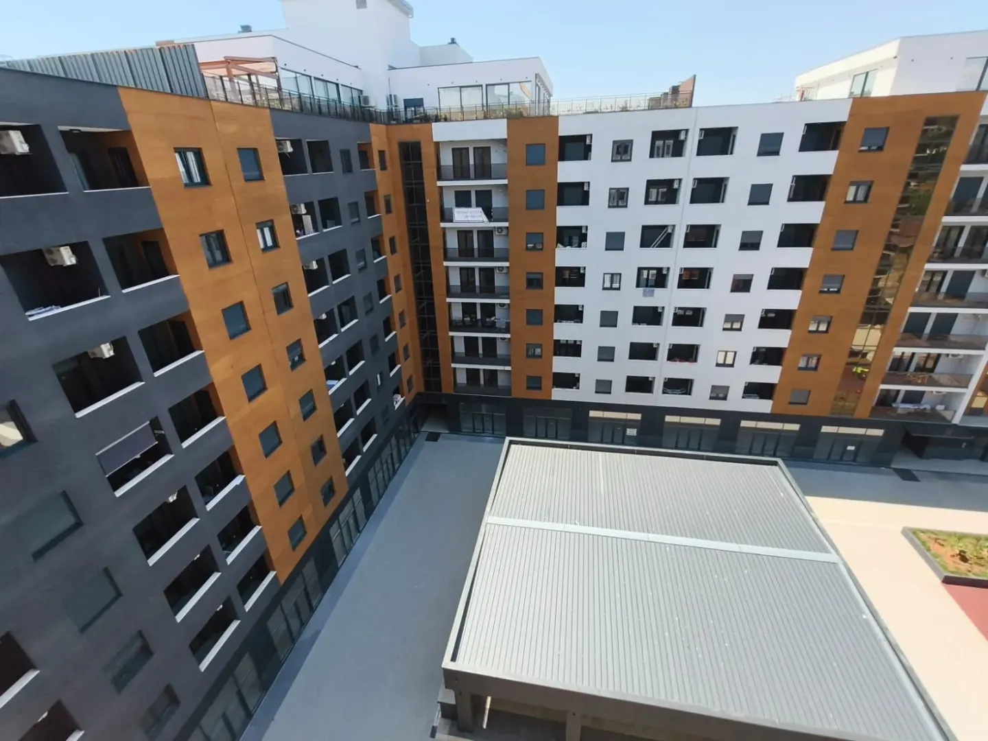 Pogled na spoljašnjost modernog stambenog kompleksa sa dvorištem.