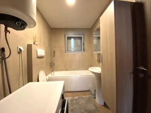 Bathroom with a bathtub, washbasin, toilet, and washing machine. - image 8