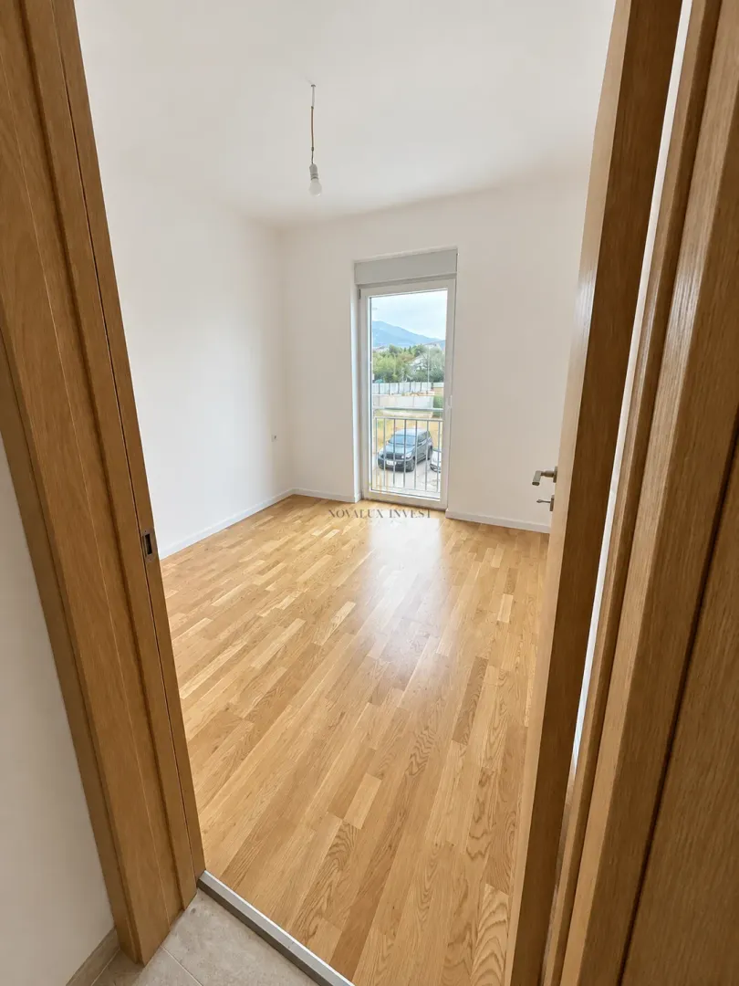 Empty room with hardwood flooring and balcony doors.