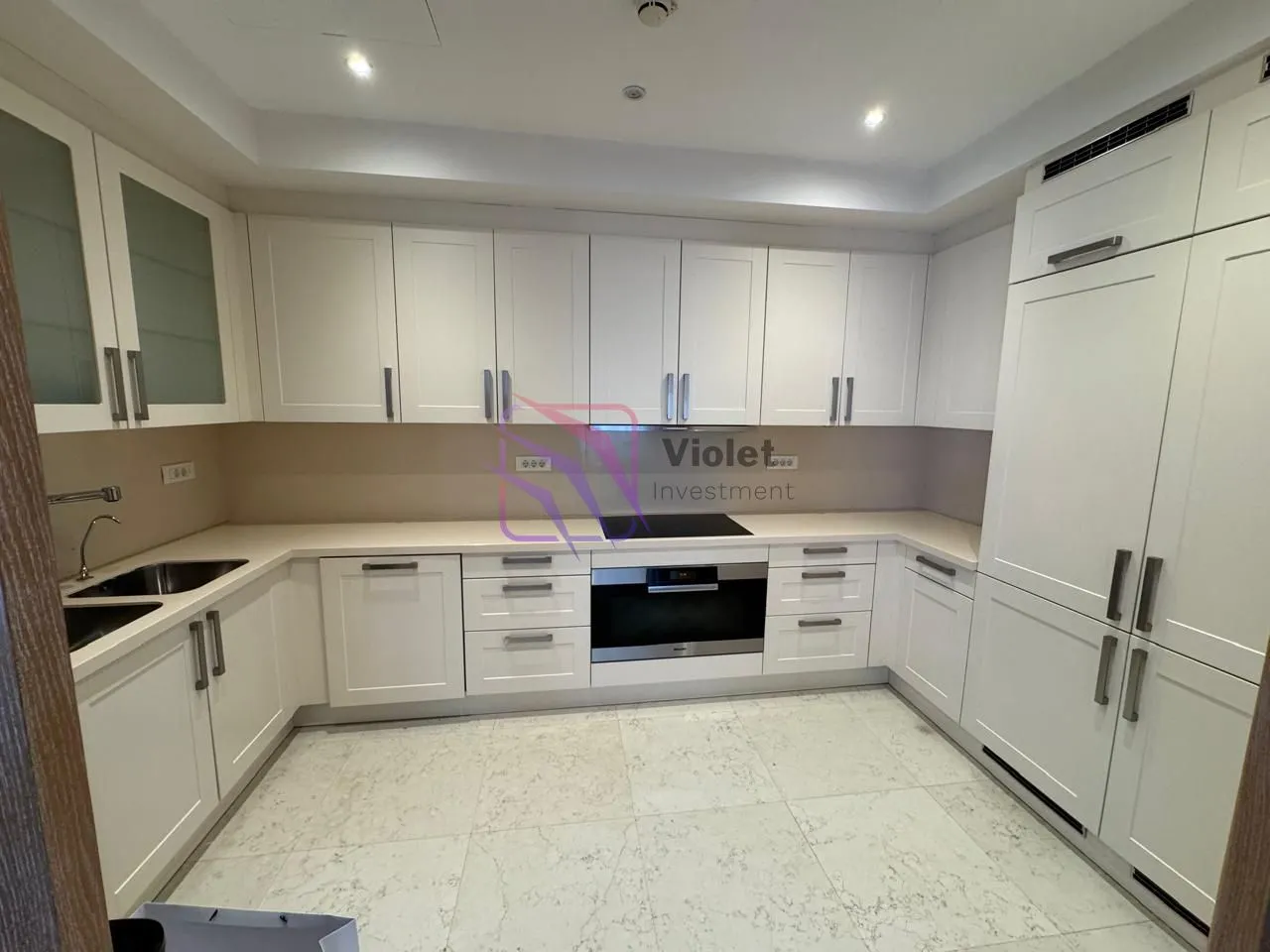 Modern white U-shaped kitchen with built-in appliances.