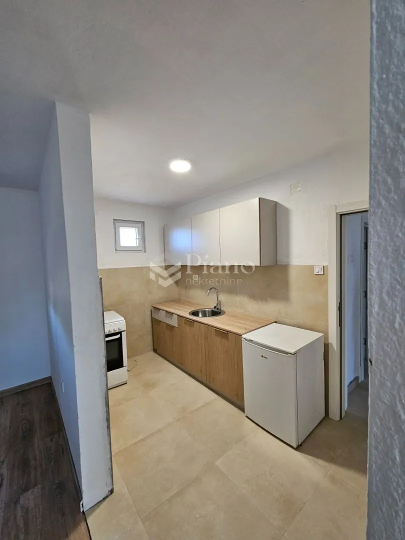 Small kitchen with wooden cabinetry, a sink, and a stove.