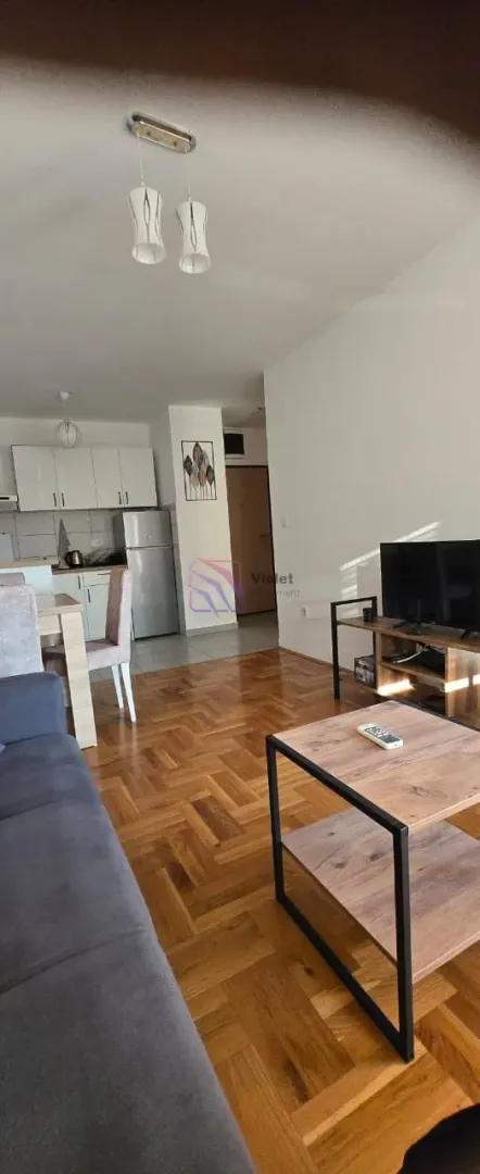 Living room with a sofa, television and a view towards the dining area and kitchen.