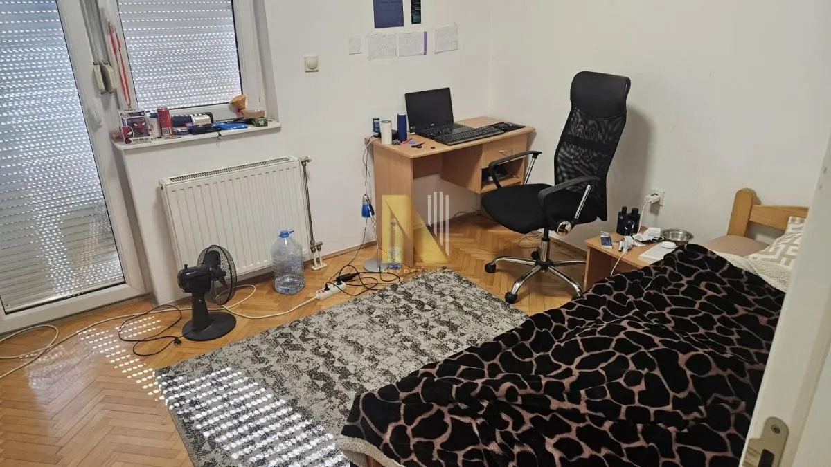 Manja spavaća soba sa krevetom, radnim stolom i izlazom na terasu.