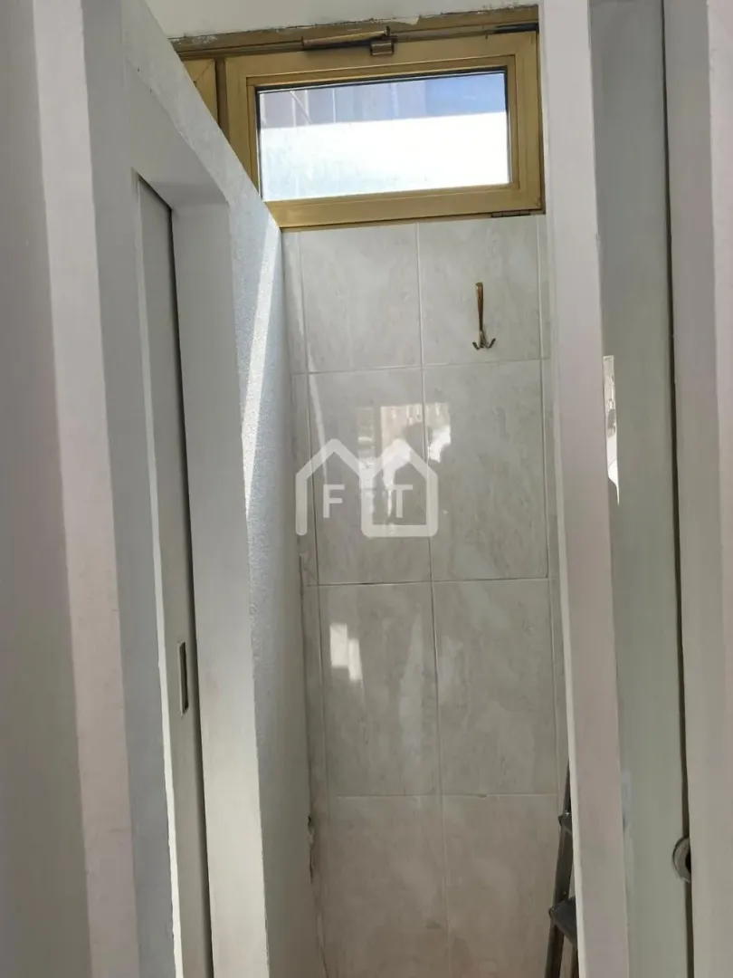 View of a small bathroom tiled with ceramic tiles.