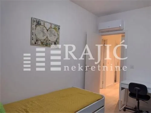 Small bedroom with a bed, desk, and air conditioning unit.