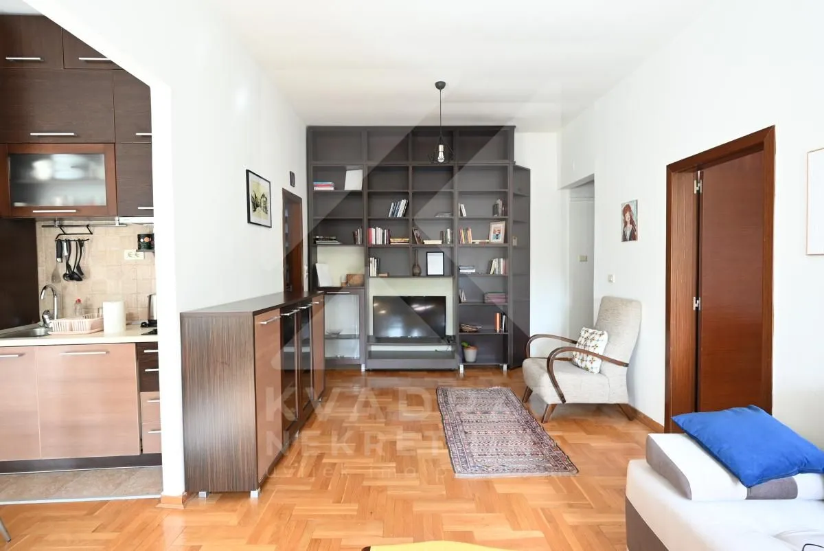 Living room connected to the kitchen, featuring a large bookcase and TV unit.