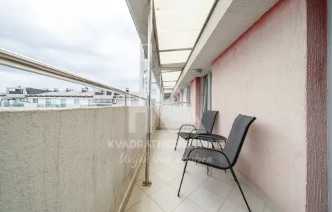 Covered balcony with chairs and a view of surrounding buildings. - image 10