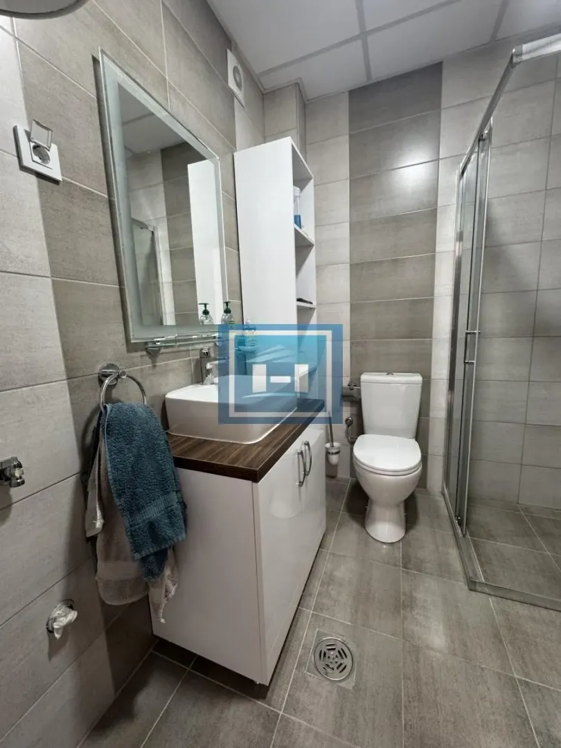 Moderno kupatilo sa tuš kabinom, umivaonikom i WC šoljom.