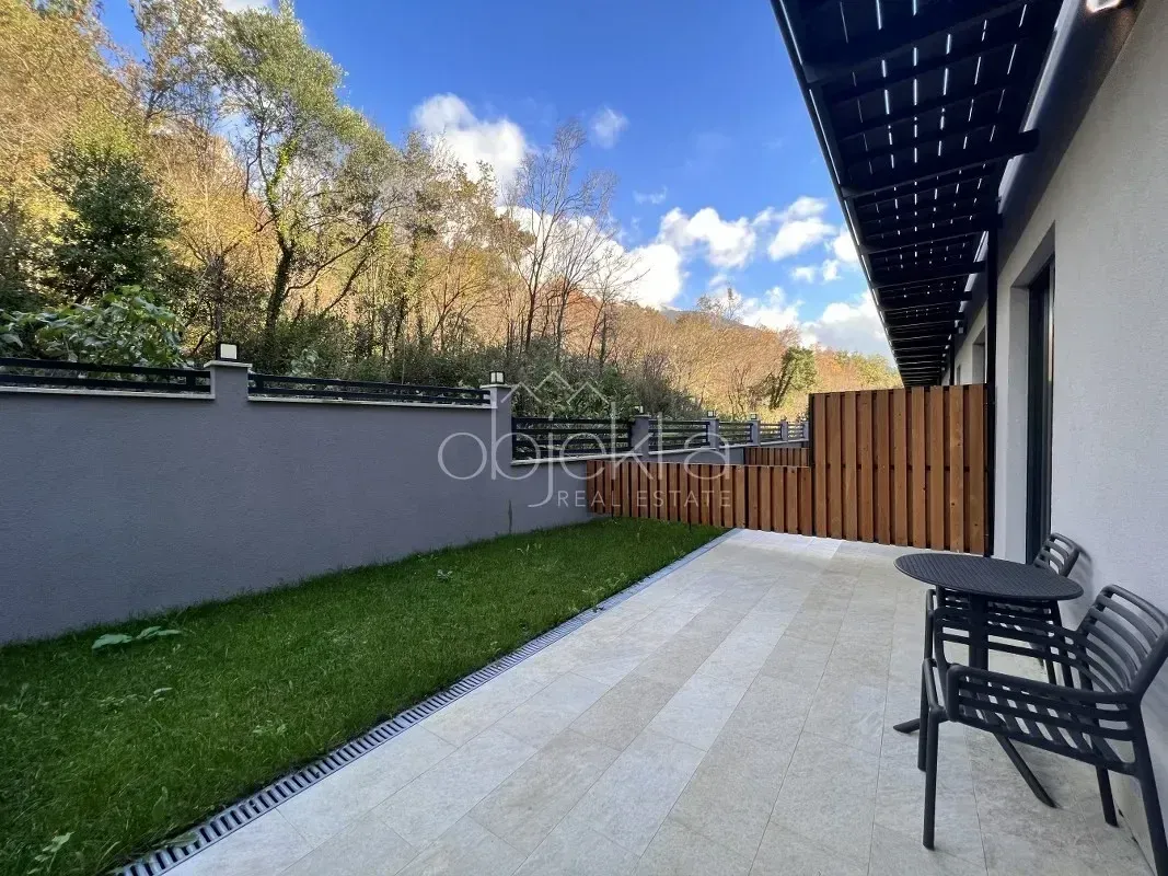 Tiled terrace with seating furniture and a yard.