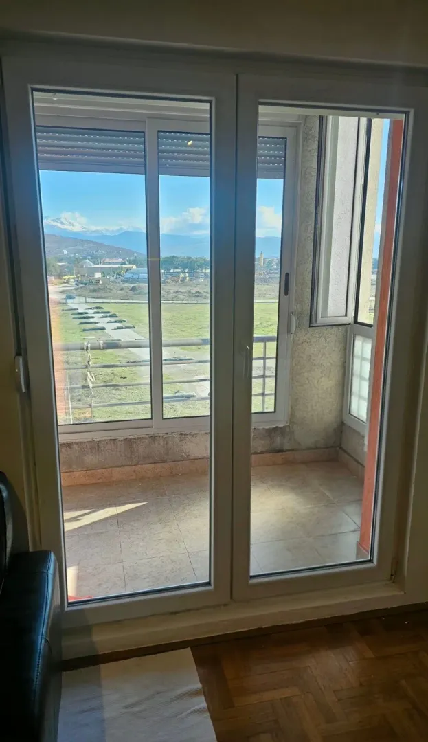 Pogled kroz balkonska vrata na terasu i okolni pejzaž.
