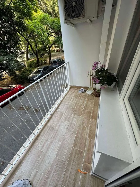 Manji svijetli balkon sa keramičkim pločicama i metalnom ogradom.