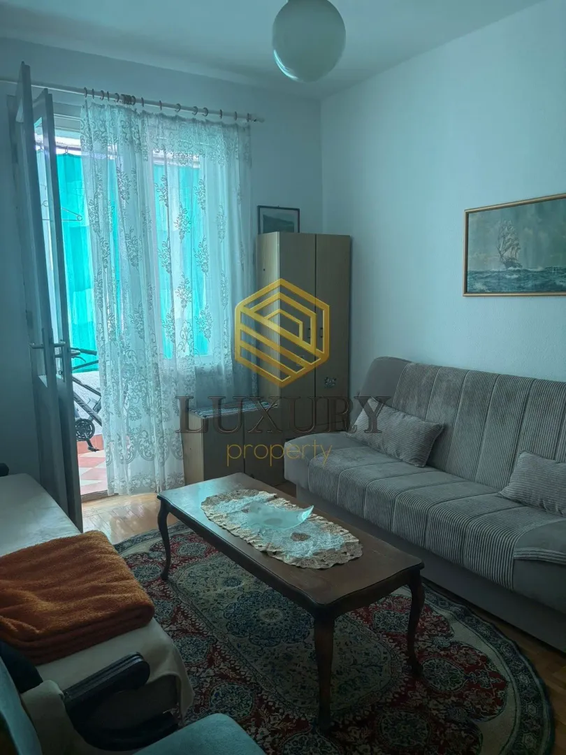 Dnevna soba sa garniturom, stočićem i izlazom na terasu.