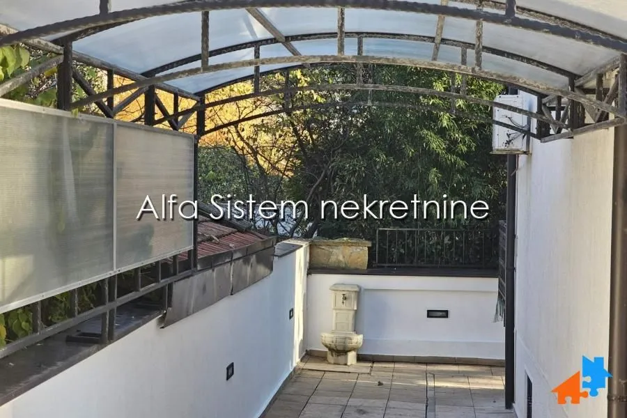 Covered walkway with a water fountain and a view of greenery.