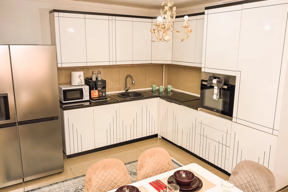 Modern kitchen with white cabinetry and a dining table.