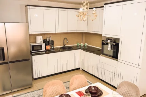 Modern kitchen with white cabinetry and a dining table. - image 9
