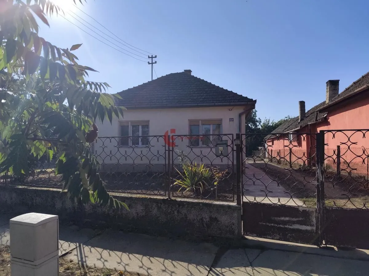 Pogled na spoljašnjost kuće sa dvorištem i ogradom.