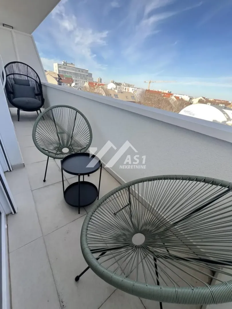 Namešten balkon sa garniturom za sedenje i pogledom na grad.