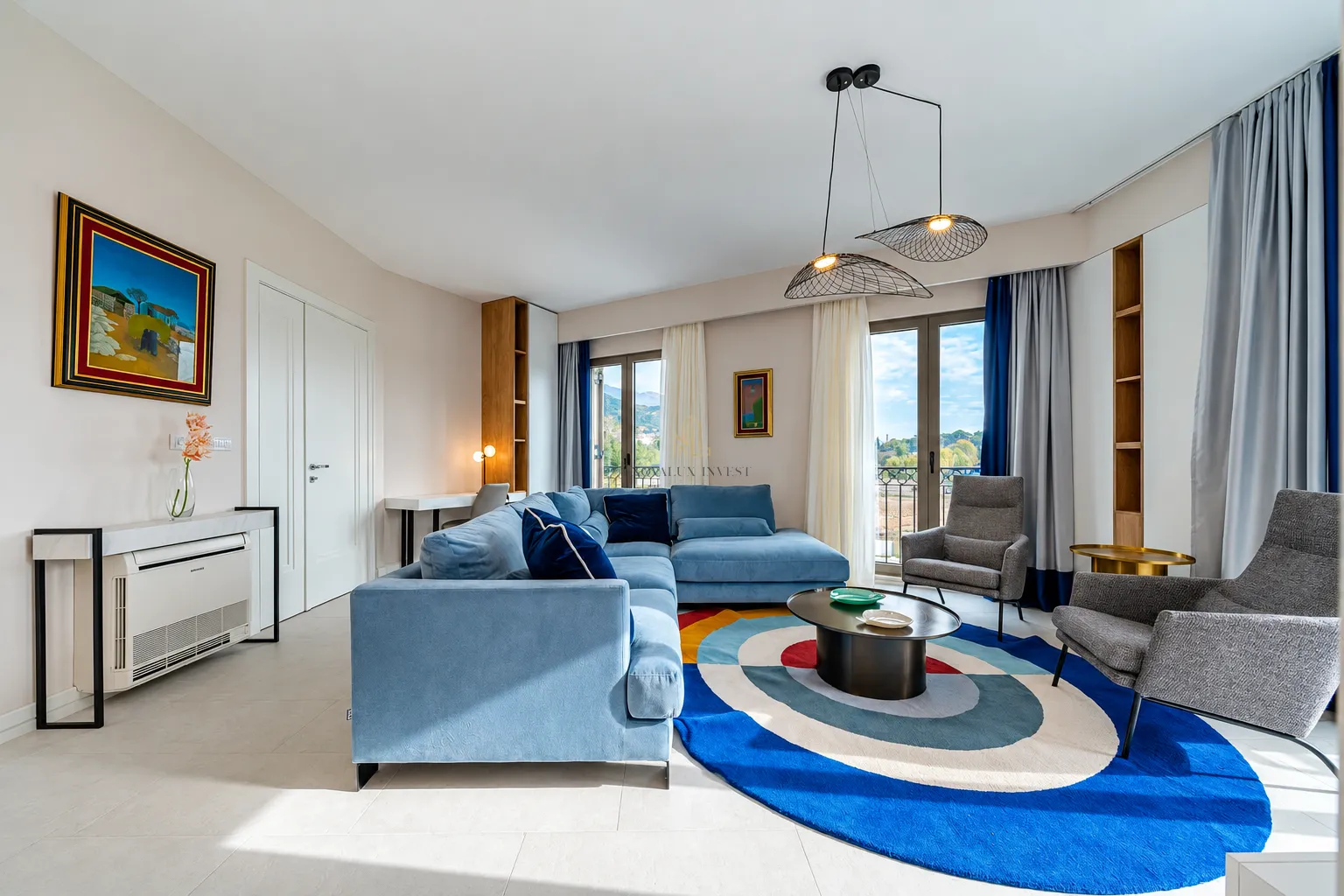 Spacious living room with a blue sectional sofa, modern pendant lights, and access to the terrace.
