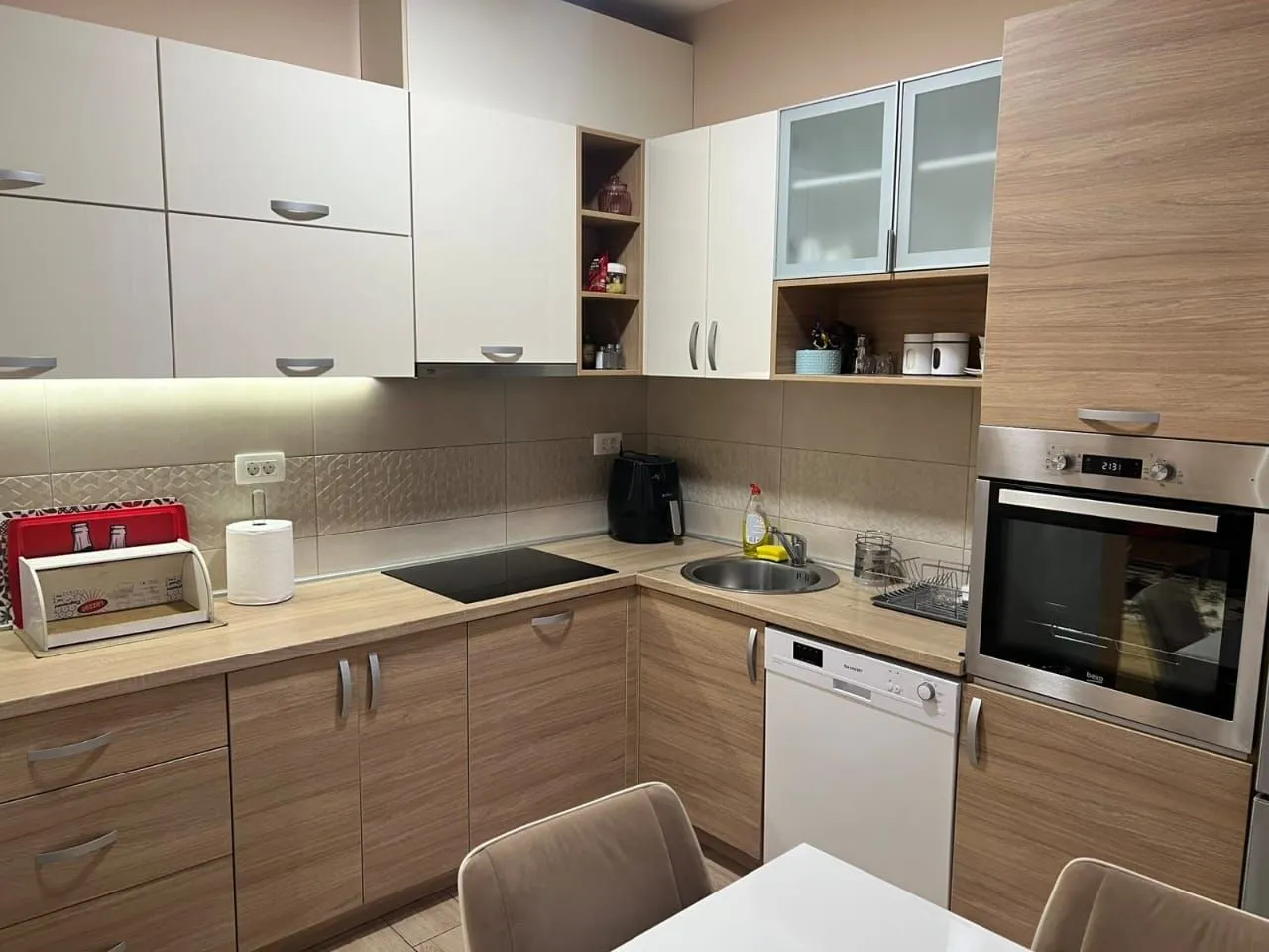Corner kitchen with wooden cabinets, sink, built-in oven, and cooktop.