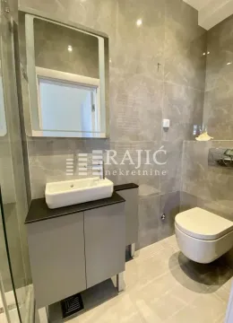 A modern equipped bathroom with a washbasin and toilet clad in ceramic tiles. - image 8