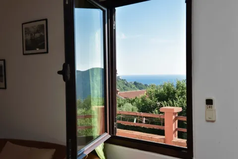View of the sea and surrounding greenery through an open window. - image 3