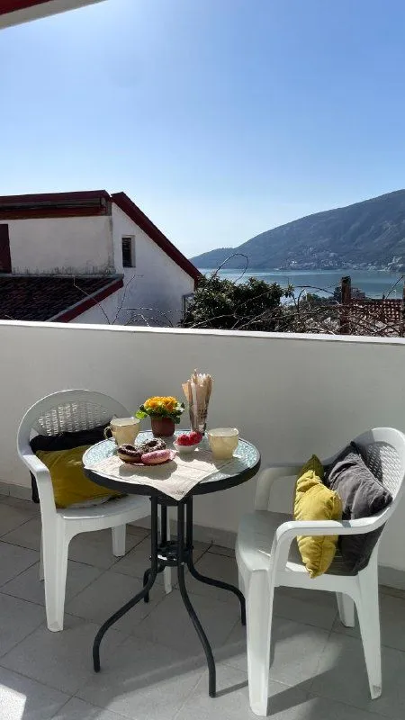 Namještena terasa sa stočićem i stolicama i pogledom na more.