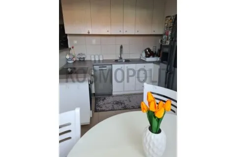 Kuhinja sa belim elementima i trpezarijskim stolom u prvom planu. - image 8