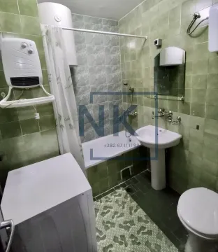Small bathroom with a bathtub, washbasin, toilet, and a water heater on the wall. - image 6