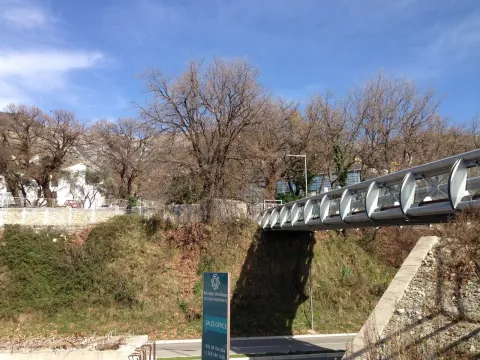 View of the building exterior featuring a pedestrian bridge and greenery. - image 14