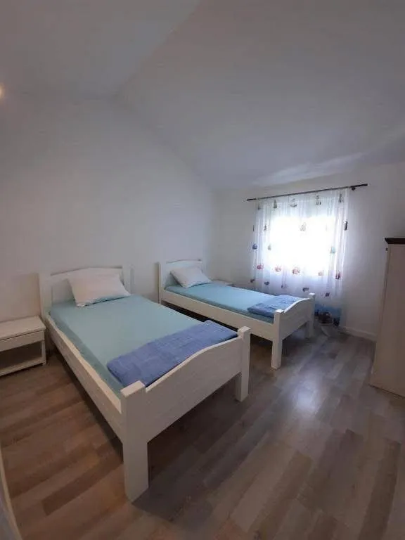 Spavaća soba sa dva odvojena kreveta i svijetlim enterijerom.