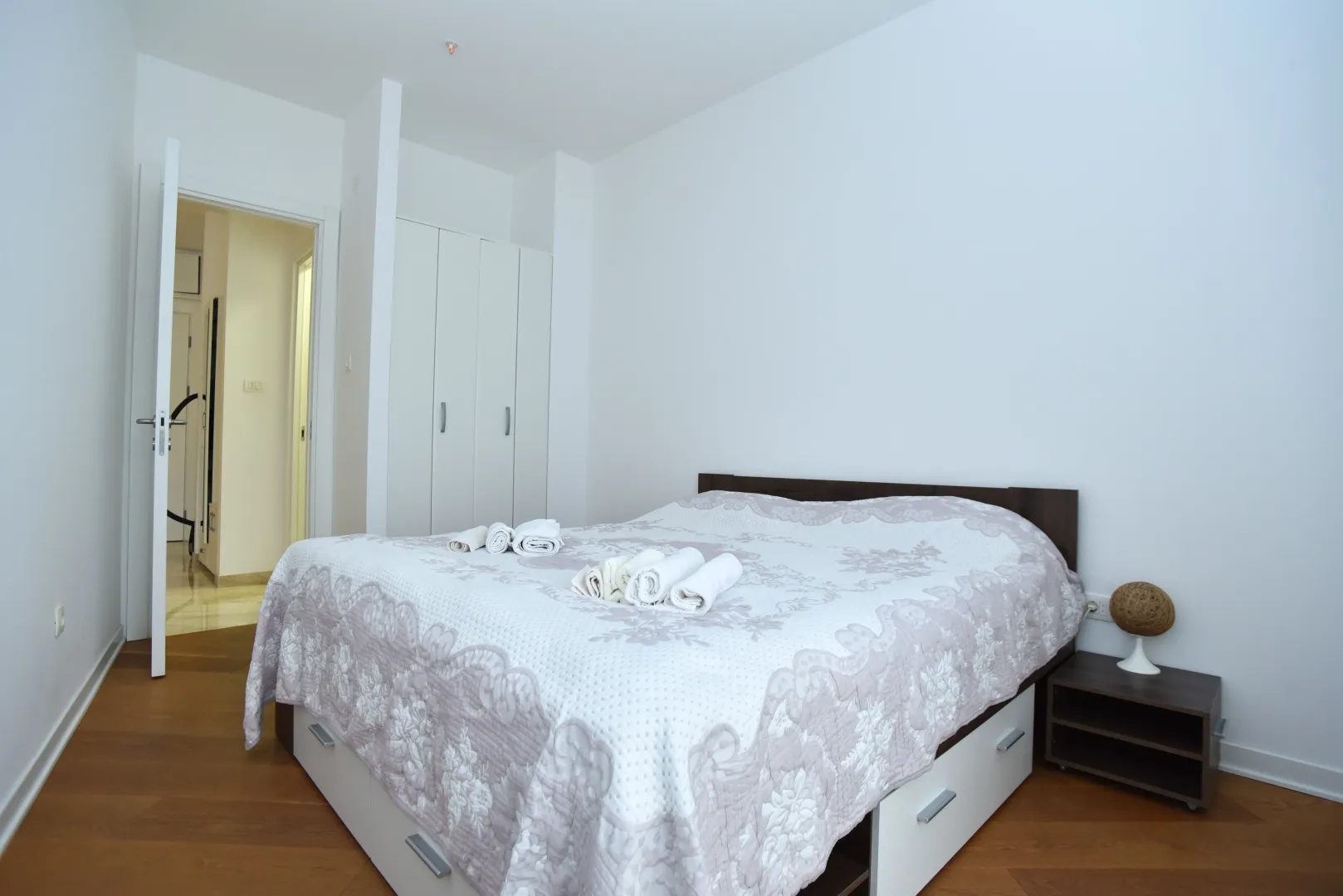 Bright and tidy bedroom with a double bed, wardrobe, and nightstand.
