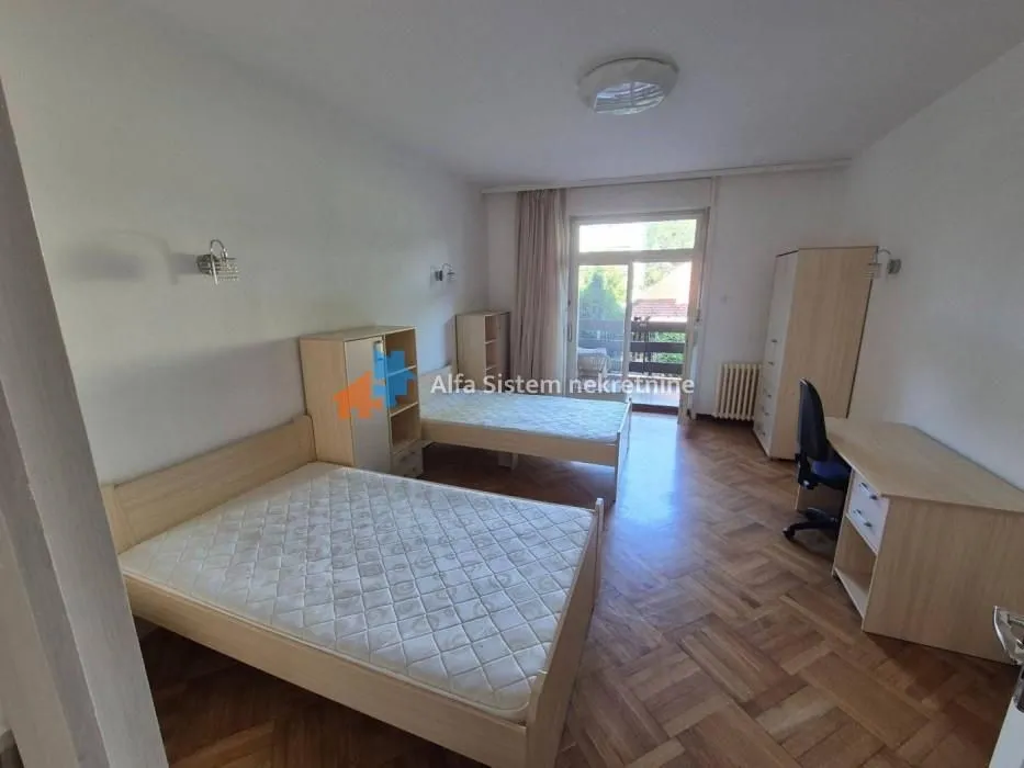 Spacious bedroom with two beds, a desk, and access to the terrace.