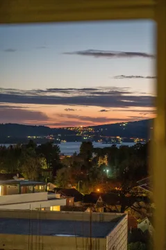 Pogled na more i grad u sumrak kroz prozor. - image 11