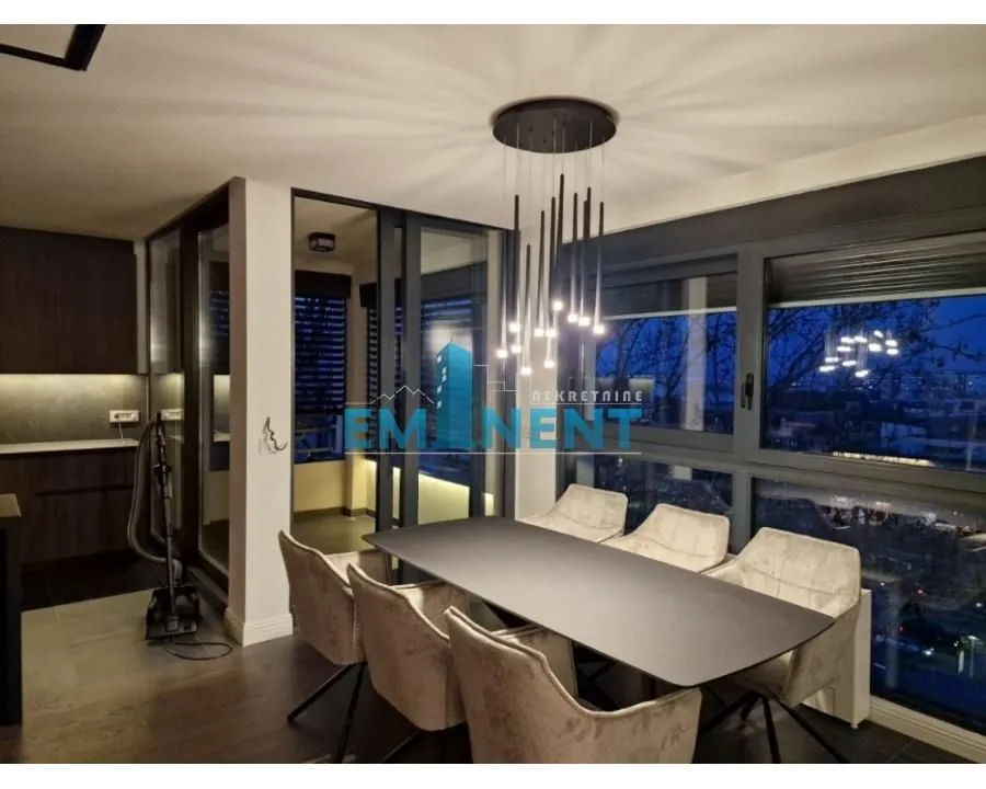 Dining area with a modern table, chairs, and chandelier as part of the living room.