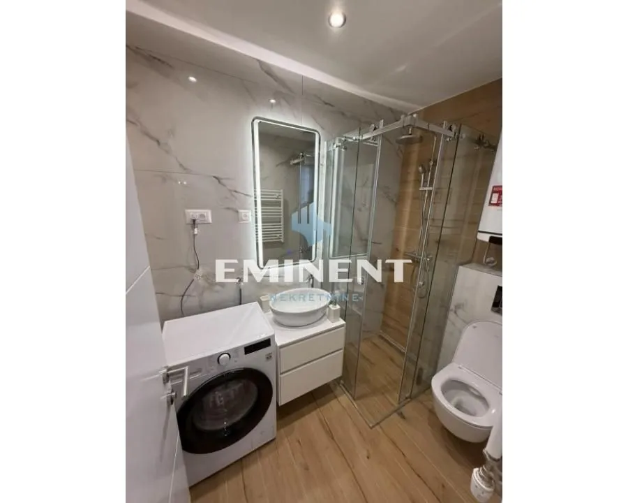 Modernly equipped bathroom with a walk-in shower and washing machine.
