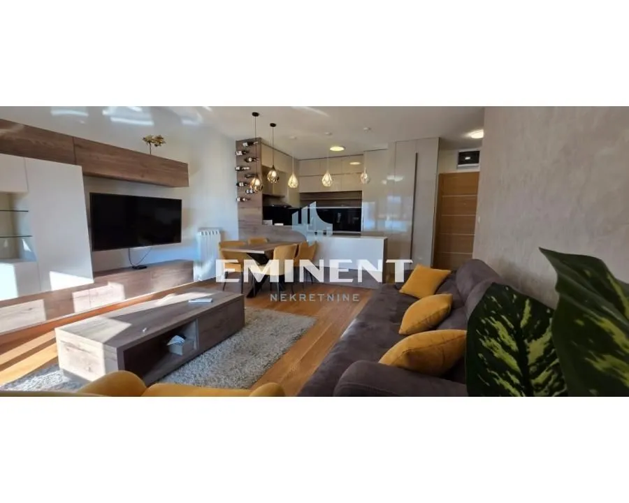Living room with a sofa, TV unit, and an adjoining dining area.