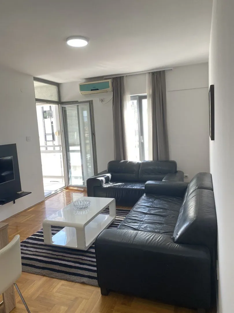 Bright living room with black leather sofas and a white coffee table.