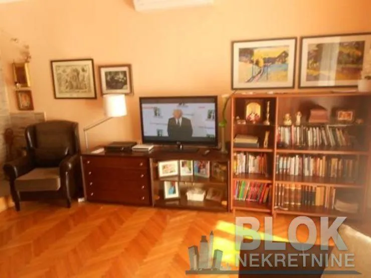 Living room with a TV, bookshelves, and an armchair.
